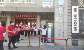 北京中考首日：十万余学生赶考，教师举“开门红”标语给考生加油