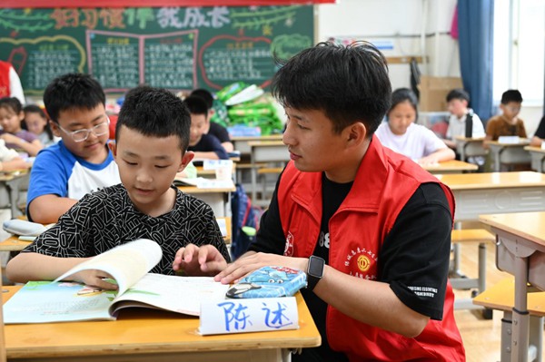 鄭州市二七區暑托班的志愿者輔導孩子寫作業。人民網記者王玉興攝