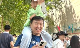5岁小朋友骑上爸爸肩头迎接姐姐出考场